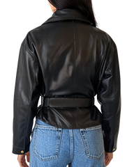 Person wearing a black leather jacket and blue jeans on a plain background