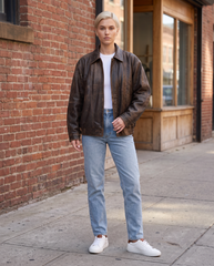 Full-length view of The Aspen women's oversized distressed brown lambskin leather jacket styled with denim.