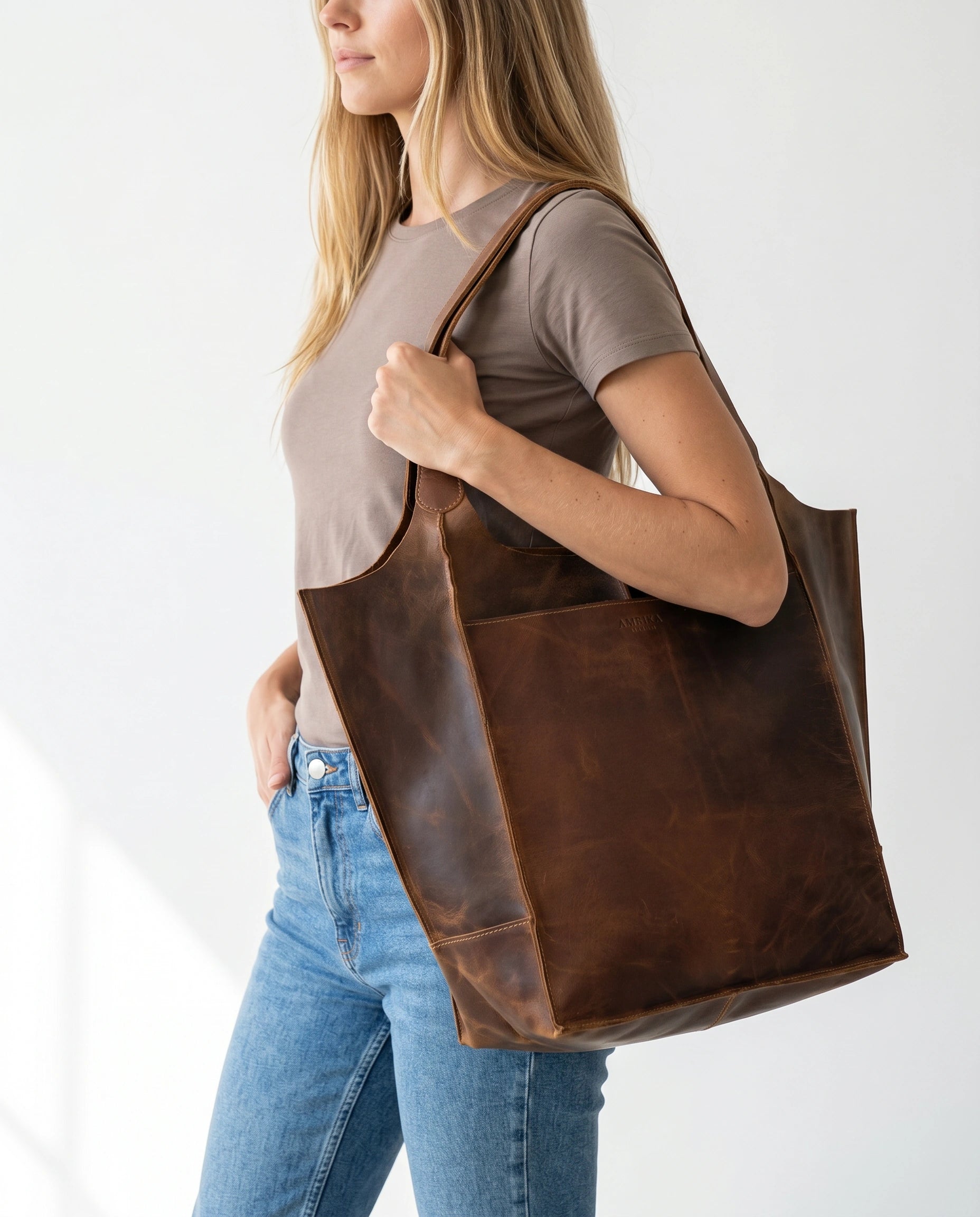 Woman carrying The Grand large buffalo leather tote bag by Amrika Leather, showcasing its oversized everyday design.